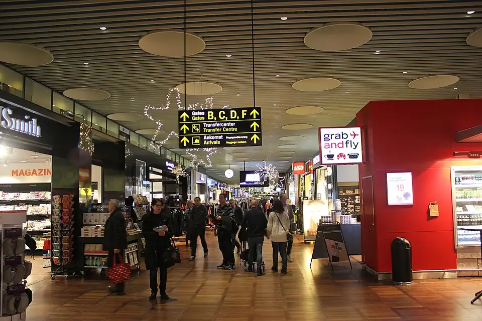 Travellers walking past shops in a terminal corridor at Copenhagen Airport