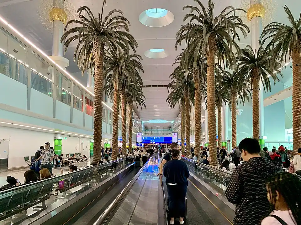 Palm trees lining a moving walkway inside Dubai International Terminal 3