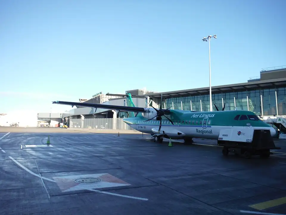 A turboprop aircraft parked on the apron beside the terminal at Dublin Airport