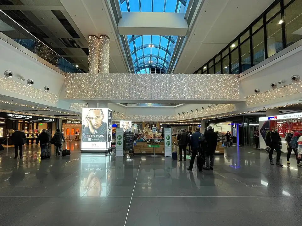 A quiet concourse of Frankfurt Airport Terminal 1 with shops on two levels and a skylight