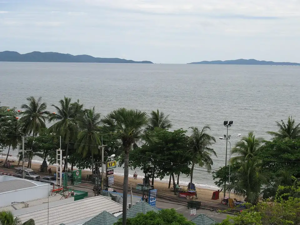 Jomtien Beach seen from above: a line of palms along the beach road, the sand and the bay with islands beyond
