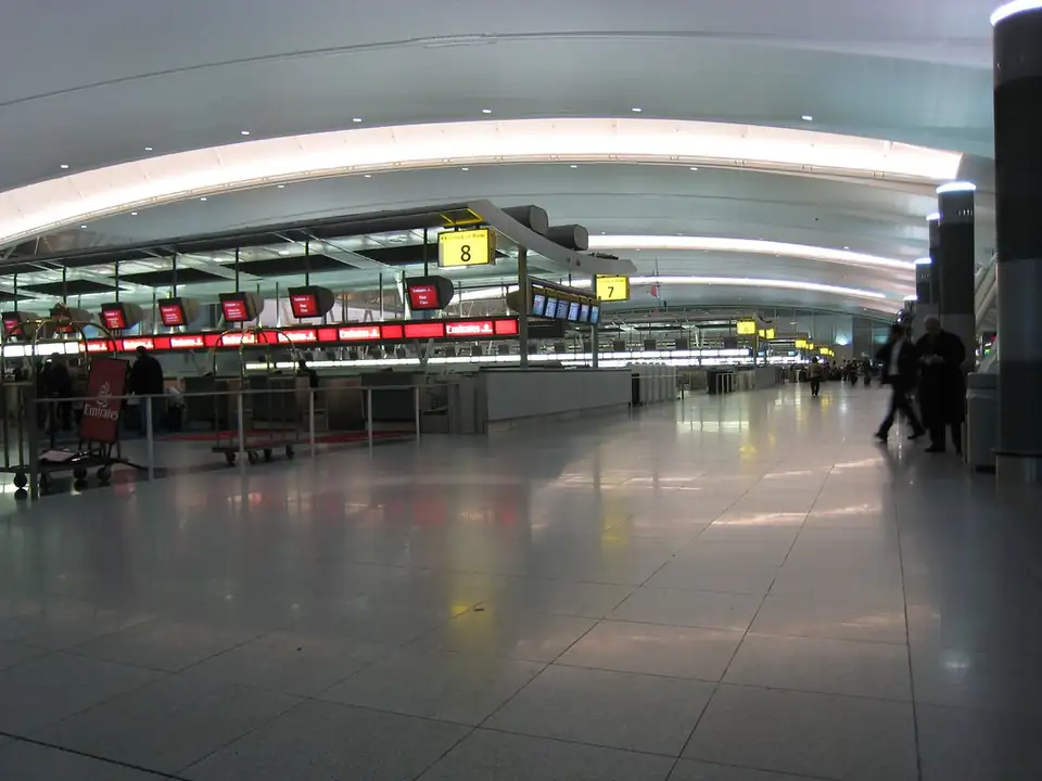 A check-in area in JFK Terminal 4 under a long curved ceiling