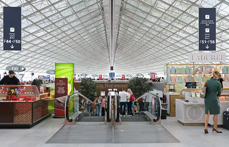 Shops and an escalator under the long latticed roof of Terminal 2F at Paris Charles de Gaulle