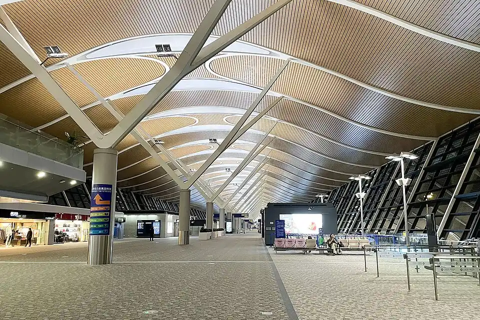 The wide departure hall of Shanghai Pudong Terminal 2 under a wave-shaped wooden roof