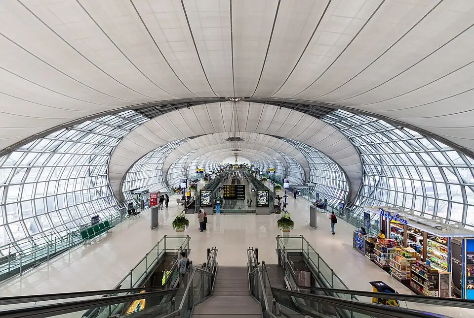 The long glass-and-steel hall of Suvarnabhumi Airport's Terminal C, with escalators and shops below