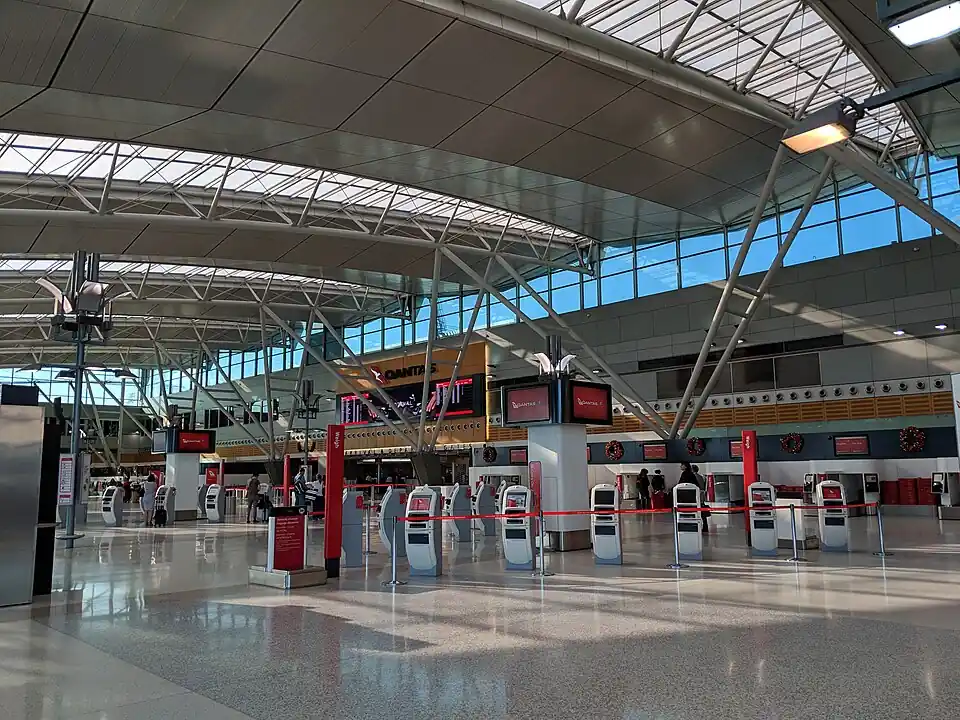 A bright check-in hall at Sydney Airport under a curved white roof