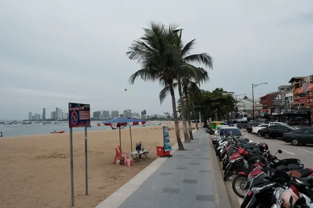 Paved Pattaya beachfront promenade between the beach and parked motorbikes